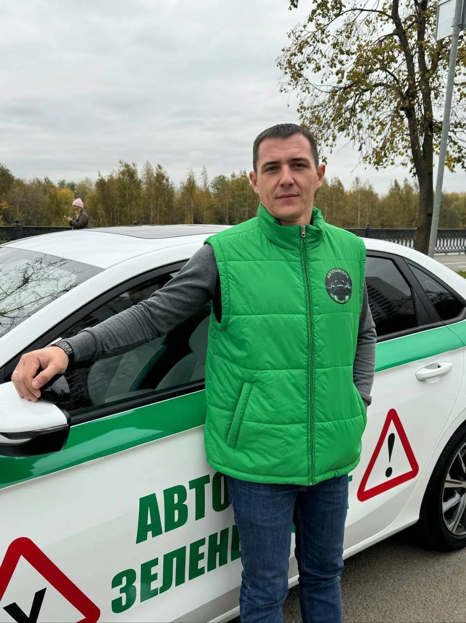 Инструктор автошколы рядом с учебным автомобилем